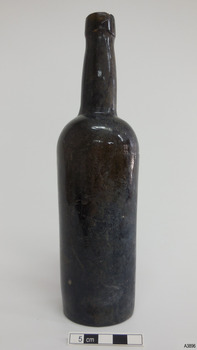 Black glass bottle is tall and slim, has an applied lip and slightly bulbous neck. There is a seam at the choulder.