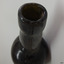Mouth has uneven edge, collar is wide and straight, with circular lines in the glass, neck is slightly bulbous and has twisted lines.