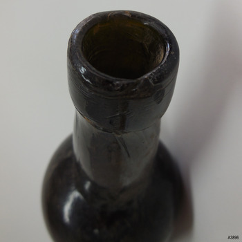 Mouth has uneven edge, collar is wide and straight, with circular lines in the glass, neck is slightly bulbous and has twisted lines.