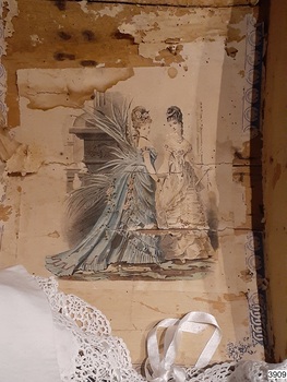 Inside of trunk's lid with pasted on coloured illustration of ladies fashion