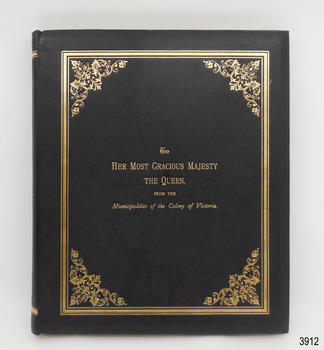 Rectangular book, portrait orientation, black textured cover, embossed gold border, patterned corners, title in gold lettering