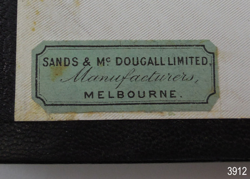Green rectangular label has maker's details in three lines.