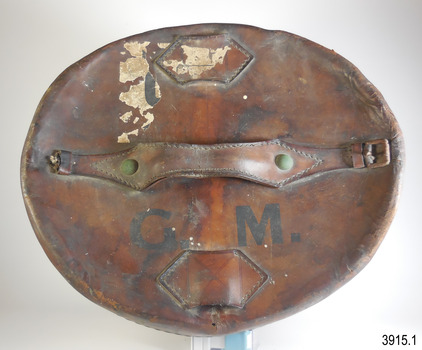 Lid showing remnants of labels, stamped initials. Two leather tags are stitched on , with a curved leather opening on one side.
