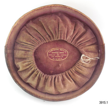Lining of lid is gathered, allowing for something to be inserted. Maker's stamp in gold lettering is printed onto lining.