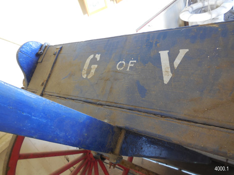 Board is painted blue and has stencilled white letters "G of V" on it. Handle is joined on under the base.