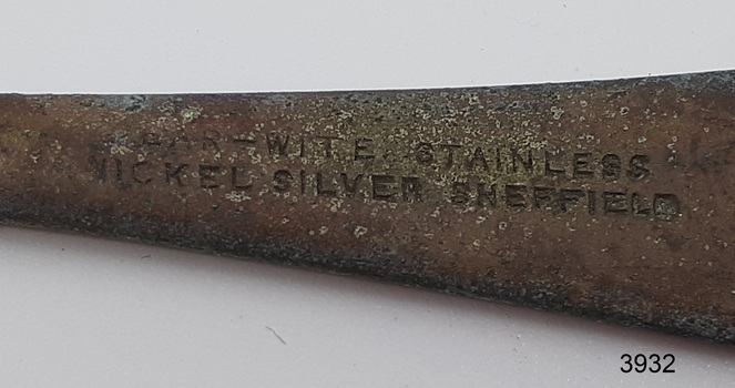 Two rows of stamped text, in capital letters. No symbols on teaspoon.