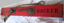 Red painted rectangular plank with two attached cable lengths joined to eyelets on metal plate