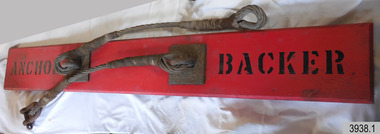 Red painted rectangular plank with two attached cable lengths joined to eyelets on metal plate