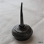Black oil bottle has round wide base and narrow tall dispensing tube