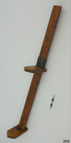 Wooden hem marker stand, leaning, with marking arm about half of the way up.
