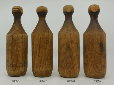 Four upright bottle-shaped wooden skittles in a line across the page. 