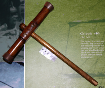 Mallet has a wooden handle and a round cross-bar. Metal reinforcing is around the ends of the head.