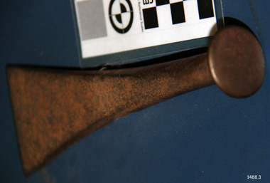 A metal tool with a round flat top and head that flares out to a wide wedge shape.