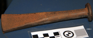 A metal tool with a round flat top, long round shank and thick narrow wedged head.
