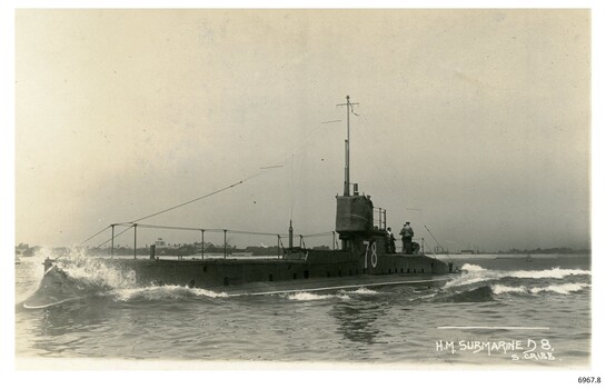 Black and white photograph of a battleship, bow stirring up the water