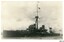 Black and white photograph, battleship sailing in cloudy weather near land