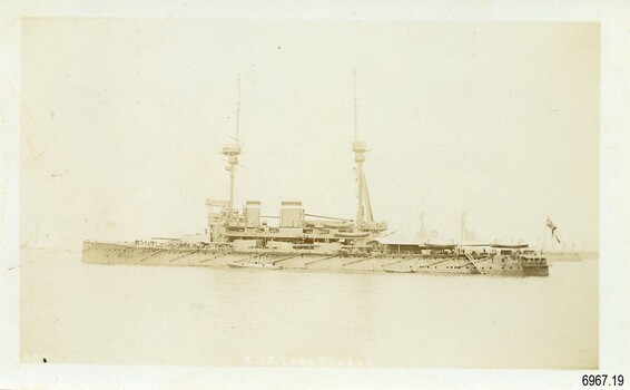 Battleship sailing in fog, flag outstretched above stern, sepia photograph