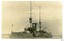 Sepia photograph of a battleship with smoking funnel