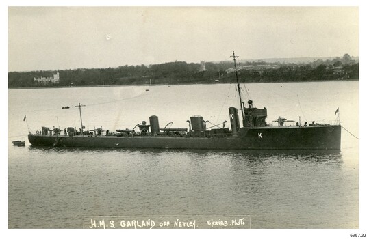 Black and white photograph of a battleship near land