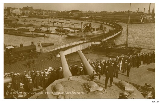 Ships in port, figures watching on in crowd. Sepia photograph