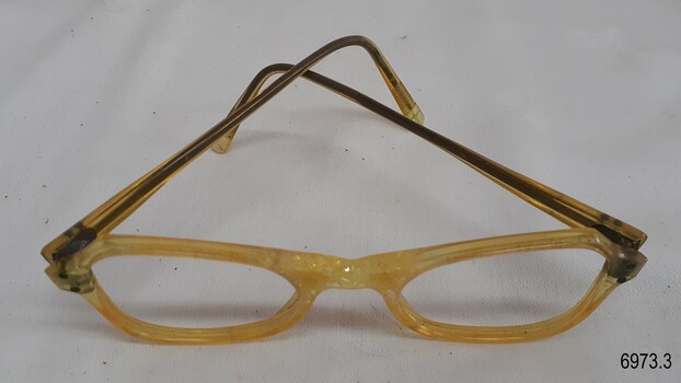Arms on opaque yellow spectacles are reinforced with metal. The nose bridge is decorated.