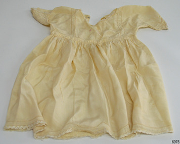 Cream silk doll's dress with smocking, embroidery and a scalloped hem.
