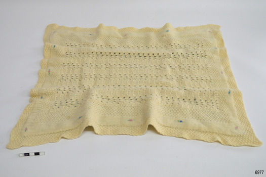 Cream coloured rectangular knitted blanket with embroidered motifs