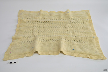 Cream coloured rectangular knitted blanket with embroidered motifs