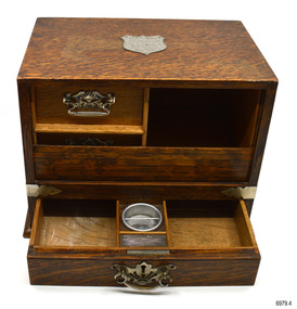 Tambour door is partly open revealing two hidden drawers and a shelf