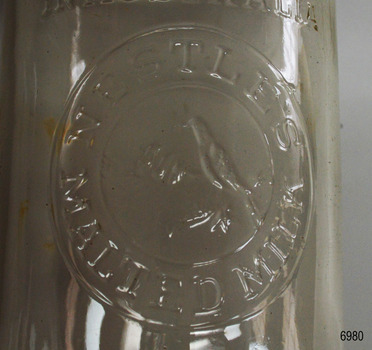 Text embossed within two concentric rings, around image of adult bird with three young in a nest.