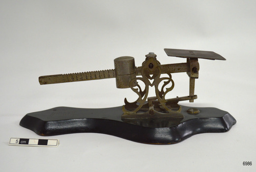 Metal and wood scale has platform and toothed balance are with weight