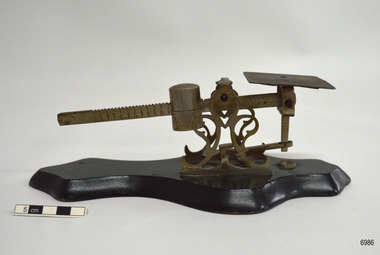 Metal and wood scale has platform and toothed balance are with weight