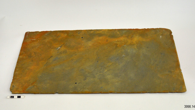 Two holes are drilled through tile, that has orange-brown stain over blue-grey colour.