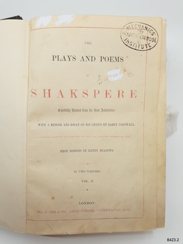 Red and black text on page, white paint, pencil writing and an oval stamp
