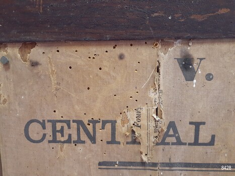 Poster has insect damage, fabric is torn, revealing newspaper beneather cloth