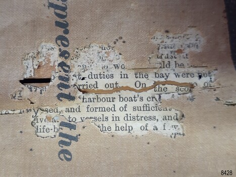 Timber backboard can be seen through tear. Newsprint is revealed between front and back