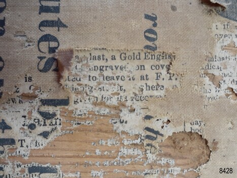 Torn and stained fabric, newsprint behind fabric.