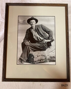  William Ferrier sitting on a log, with the photograph mounted in a brown frame