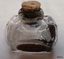 Cork in mouth of bottle, shoulders have indents on each corner, sloping down and outwards