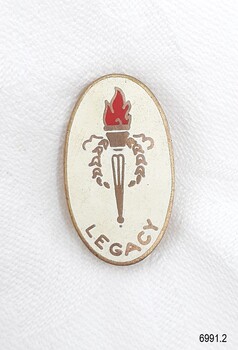Gold metal and white enamel badge with symbol of flaming torch