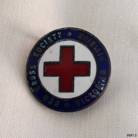 Metal and enamel badge. Blue outer ring, white centre circle behind a red cross.