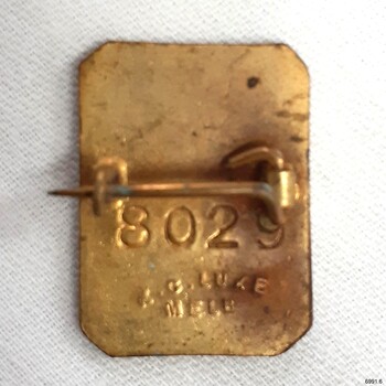 Reverse has a horizontal pin and stamped and embossed inscriptions