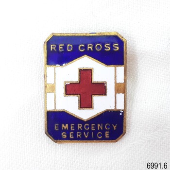   Rectangular shaped badge with blue enamel top and bottom thirds, white and gold bands across the centre with a red cross