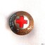 Dome-shaped round brass badge with white enamel centre section behind red enamel cross. 