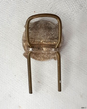 Metal badge has a vertical steel pin