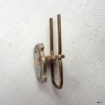 Badge's fitting has space between front and pin, allowing for fabric between them