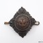 Metal badge is diamond-shaped. It has an inscription and three crown logos.