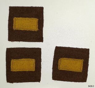 Three fabric badges, yellow rectangles on brown squares.