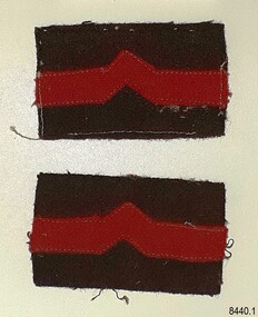 Pair of patches, red stripe with inverted 'V' on brown fabric. One has stitching.
