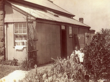 Black and white photograph of adult and two children in front of a building